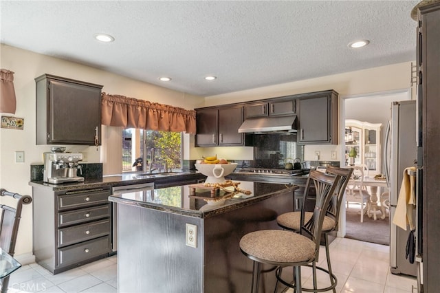 kitchen featuring sink, appliances with stainless steel finishes, dark brown cabinets, and a center island