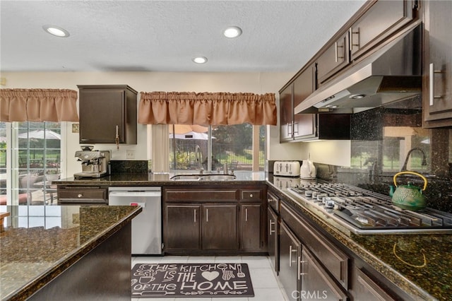 kitchen with sink, appliances with stainless steel finishes, dark stone countertops, and dark brown cabinetry