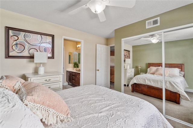 carpeted bedroom with a closet, ceiling fan, and ensuite bath