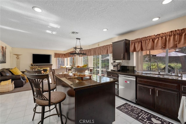kitchen featuring sink, dishwasher, a kitchen island, hanging light fixtures, and a breakfast bar area