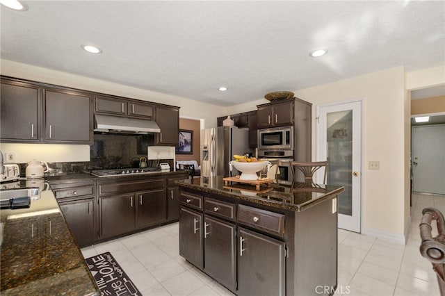 kitchen with dark stone counters, stainless steel appliances, dark brown cabinetry, and a center island