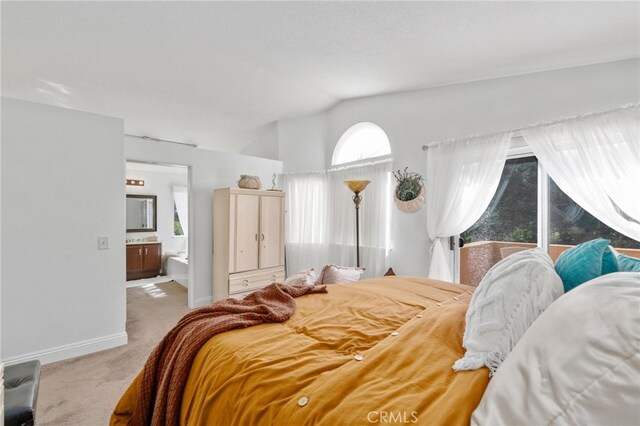 carpeted bedroom featuring lofted ceiling and ensuite bathroom