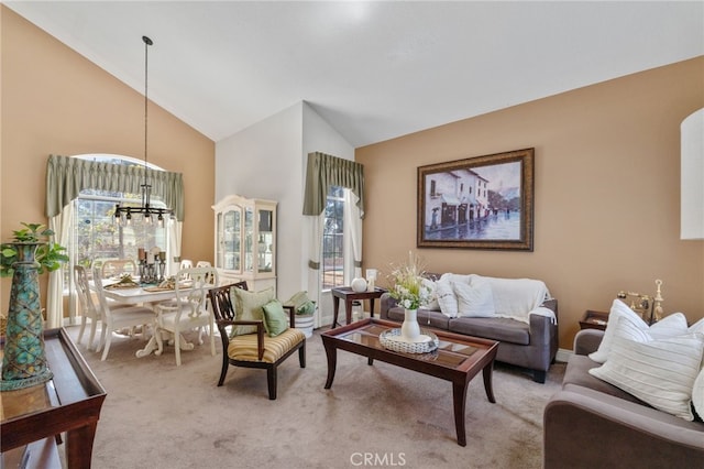 carpeted living room with a notable chandelier and high vaulted ceiling