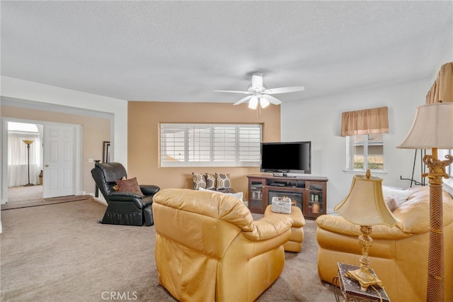 carpeted living room with a textured ceiling, ceiling fan, and a wealth of natural light