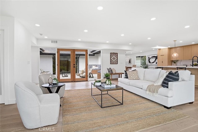 living room with recessed lighting, french doors, visible vents, and light wood-style flooring