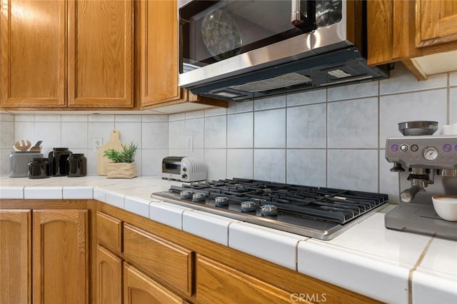 kitchen with stainless steel appliances, tasteful backsplash, and tile counters