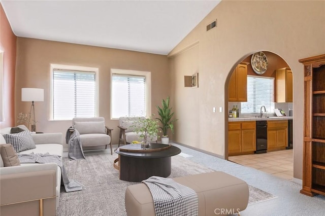 living room featuring light colored carpet, high vaulted ceiling, a healthy amount of sunlight, and sink