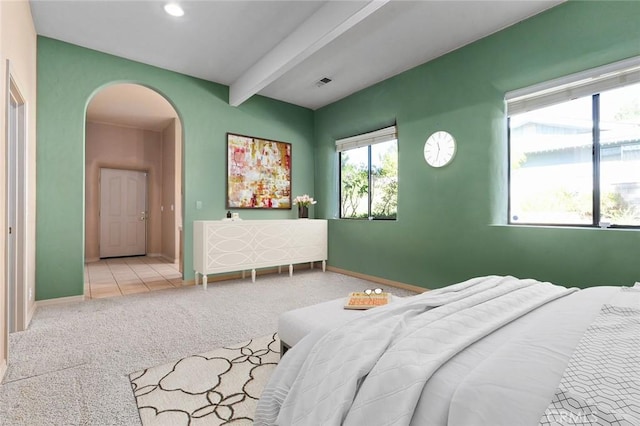 bedroom with light colored carpet and beamed ceiling