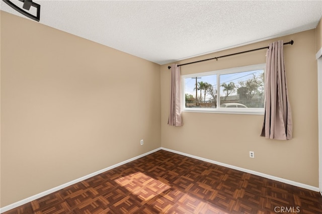 spare room featuring dark parquet floors and a textured ceiling