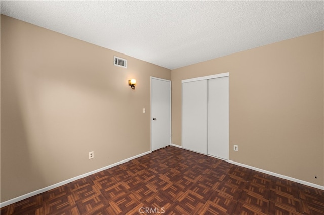 unfurnished bedroom with a closet, dark parquet floors, and a textured ceiling