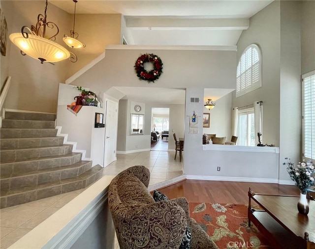 living room with a high ceiling, plenty of natural light, beam ceiling, and light hardwood / wood-style flooring