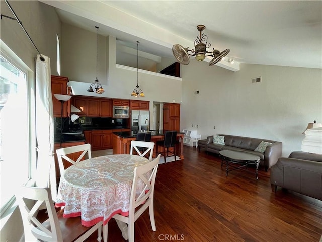 dining area with high vaulted ceiling, dark wood-type flooring, and a chandelier