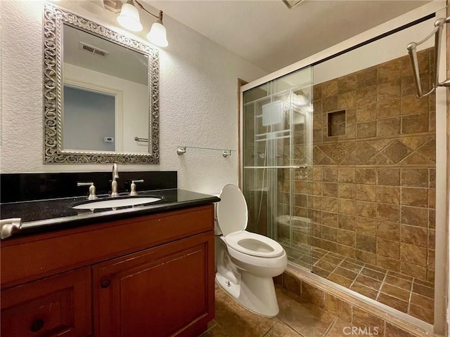 bathroom featuring vanity, a shower with door, and toilet