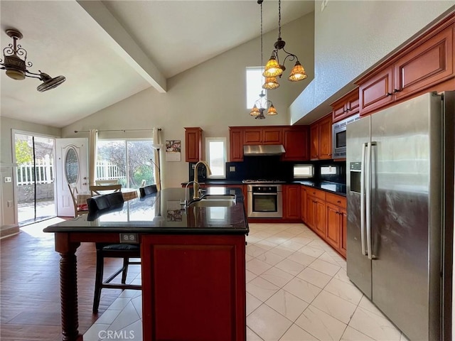 kitchen featuring a kitchen bar, sink, appliances with stainless steel finishes, an island with sink, and beam ceiling