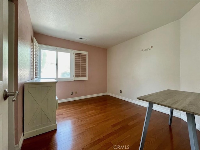 empty room with wood-type flooring and a textured ceiling