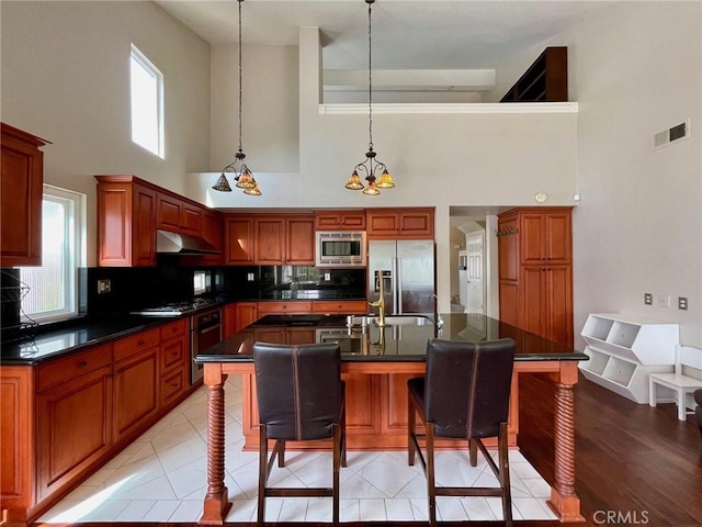 kitchen featuring a breakfast bar, decorative light fixtures, sink, a kitchen island with sink, and stainless steel appliances