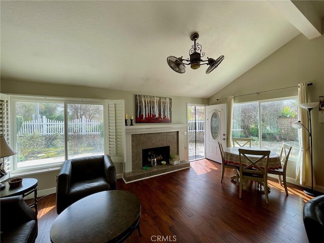 living room with a tiled fireplace, vaulted ceiling, and hardwood / wood-style floors