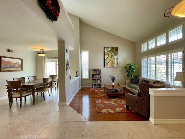 living room featuring high vaulted ceiling and light tile patterned floors