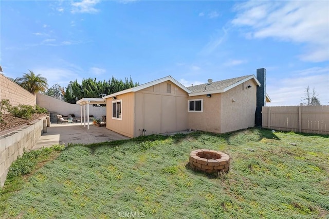 rear view of house featuring a patio area, a lawn, and an outdoor fire pit