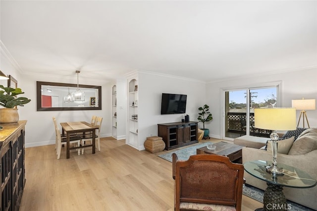 living area featuring ornamental molding, a notable chandelier, light wood-style flooring, and baseboards