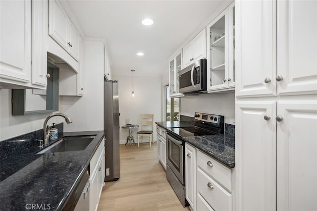 kitchen with dark stone counters, stainless steel appliances, a sink, and white cabinetry