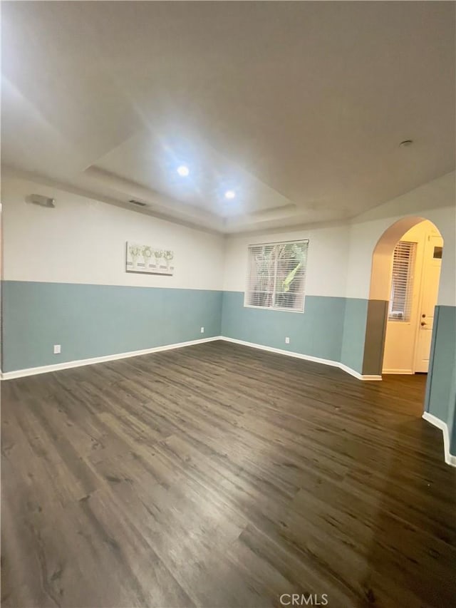 unfurnished room with a raised ceiling and dark wood-type flooring