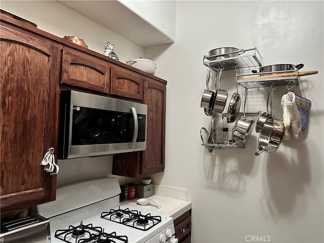 kitchen with white gas stove and dark brown cabinetry