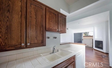 kitchen with sink, dark hardwood / wood-style flooring, dishwasher, and tile counters