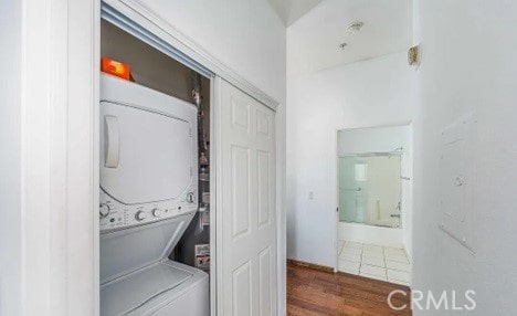 laundry area with stacked washer / dryer and dark hardwood / wood-style floors