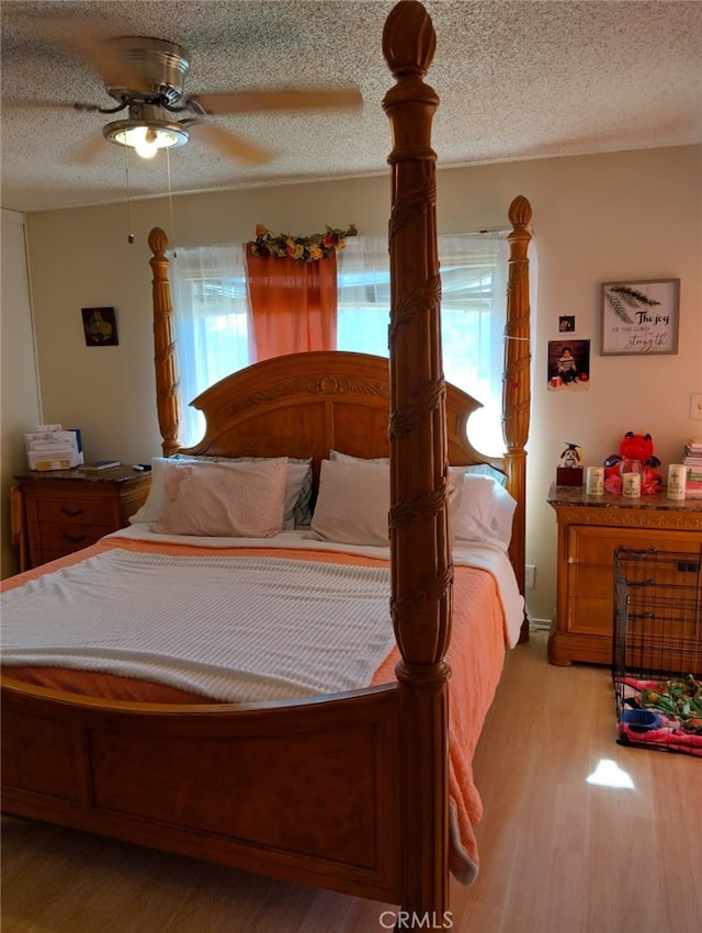 bedroom with ceiling fan, light hardwood / wood-style floors, and a textured ceiling