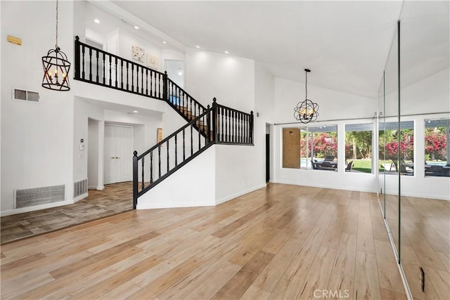 unfurnished living room featuring a chandelier, a high ceiling, and light wood-type flooring