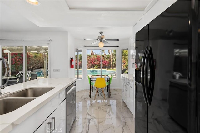 kitchen featuring sink, black fridge with ice dispenser, plenty of natural light, and white cabinets