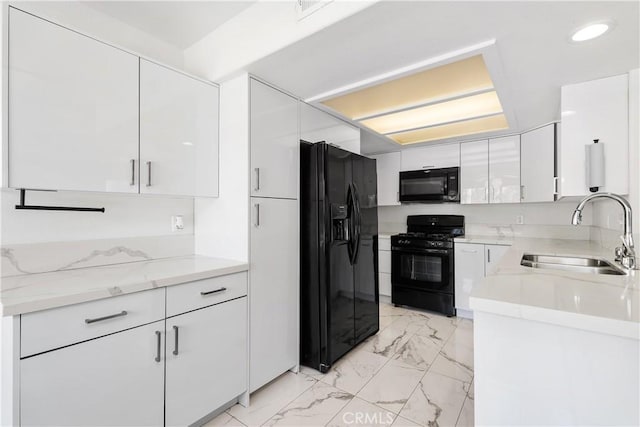 kitchen featuring white cabinetry, sink, light stone counters, and black appliances