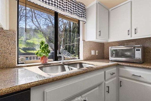 kitchen featuring sink, white cabinets, light stone countertops, and decorative backsplash