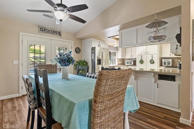 dining room with ceiling fan, lofted ceiling, dark hardwood / wood-style flooring, and french doors