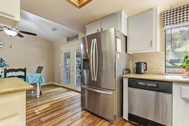 kitchen with backsplash, appliances with stainless steel finishes, white cabinets, and light hardwood / wood-style floors