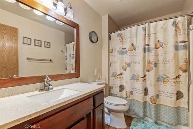 bathroom with toilet, vanity, and walk in shower