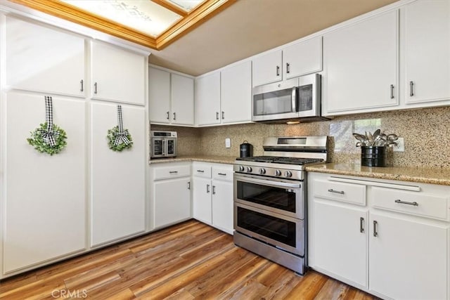 kitchen featuring white cabinetry, backsplash, stainless steel appliances, and light hardwood / wood-style flooring