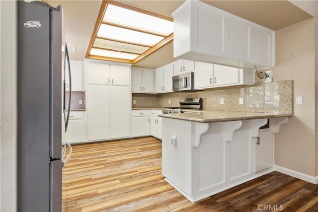 616 Jackson Dr, Paso Robles, CA 93446 - kitchen featuring stainless steel appliances, a peninsula, light wood finished floors, and backsplash