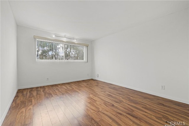 empty room featuring wood finished floors and baseboards