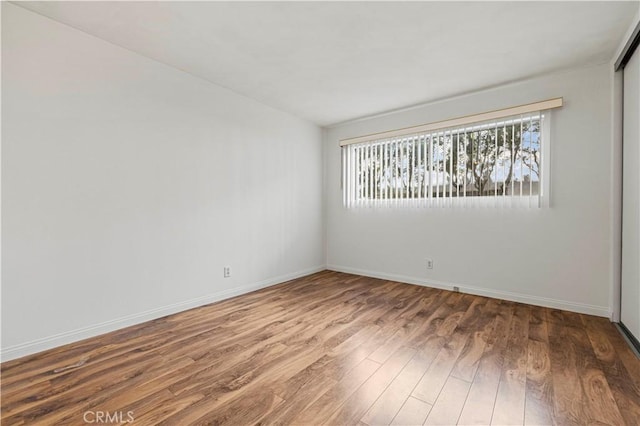 unfurnished room featuring baseboards and wood finished floors