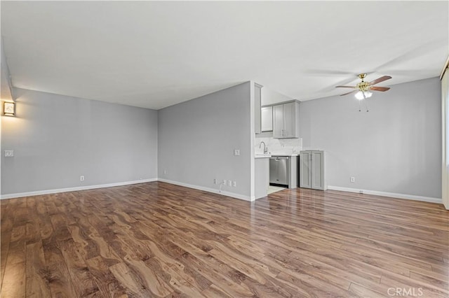 unfurnished living room featuring baseboards, wood finished floors, and ceiling fan