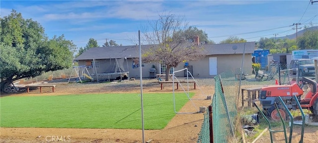 back of house with a trampoline and a lawn