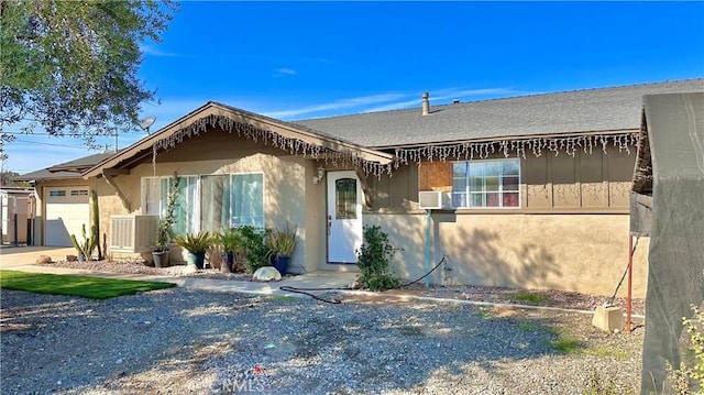 view of front of house featuring stucco siding, cooling unit, and an attached garage