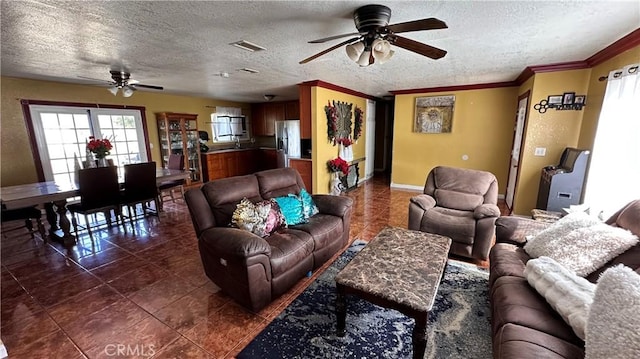 living area featuring crown molding, visible vents, ceiling fan, and a textured ceiling