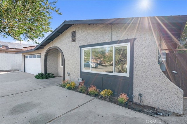 view of front of home featuring an attached garage, driveway, fence, and stucco siding