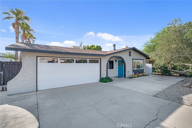 single story home with driveway, a garage, fence, and stucco siding