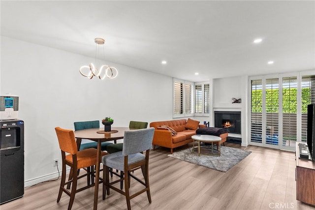 7826 Topanga Canyon Blvd Unit 101, Canoga Park, CA 91304 - dining room featuring light wood finished floors, recessed lighting, a chandelier, a warm lit fireplace, and baseboards