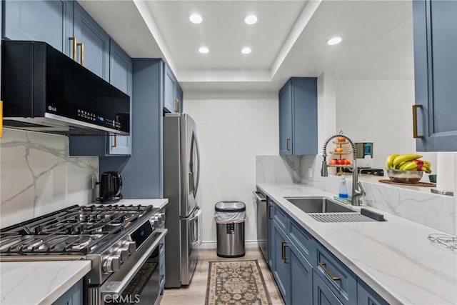 kitchen with blue cabinets, light stone countertops, appliances with stainless steel finishes, and a sink