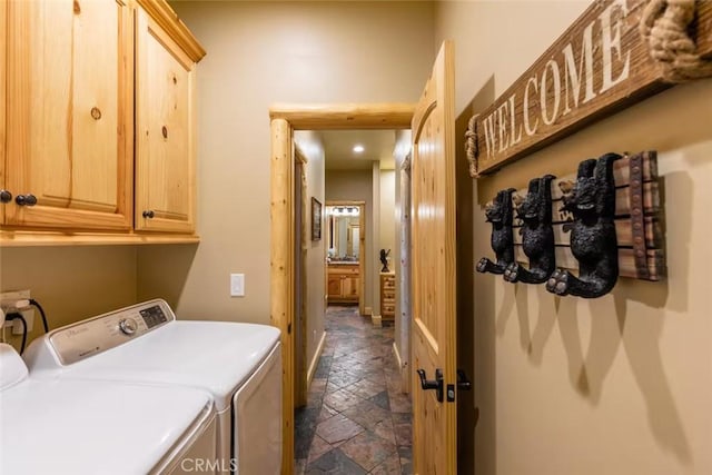clothes washing area featuring washing machine and clothes dryer, stone tile flooring, and cabinet space